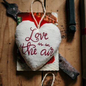 cuore di san valentino con ricamata la frase "love is in the air"